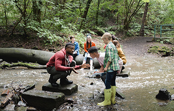 Image of teacher with young students exploring a creek