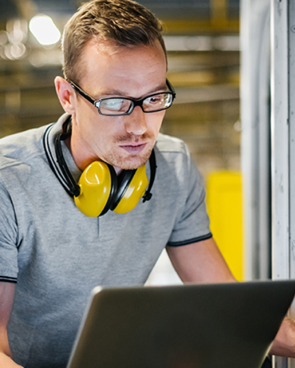 Man sitting, looking at a laptop