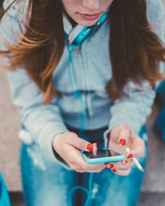 Young woman sitting, smoking, while on her cell phone