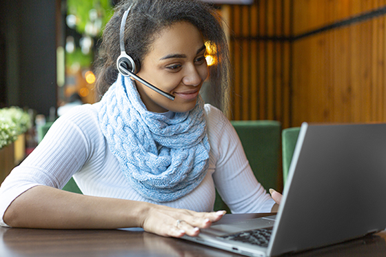 Image of woman at laptop with a headset