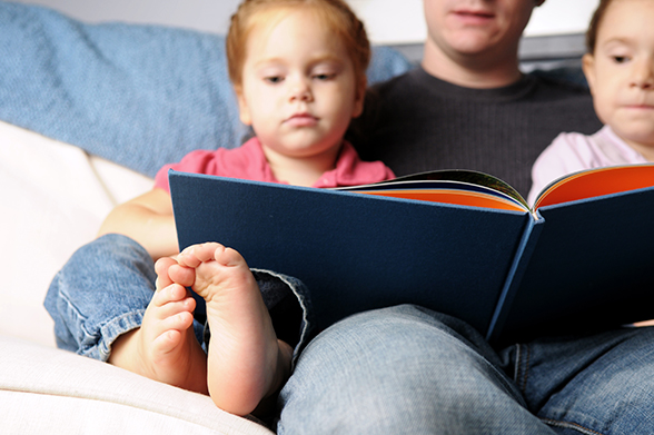 Image of dad and small children reading together