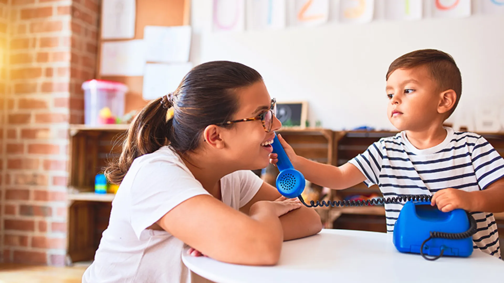 Teacher and young student playing with toy phone