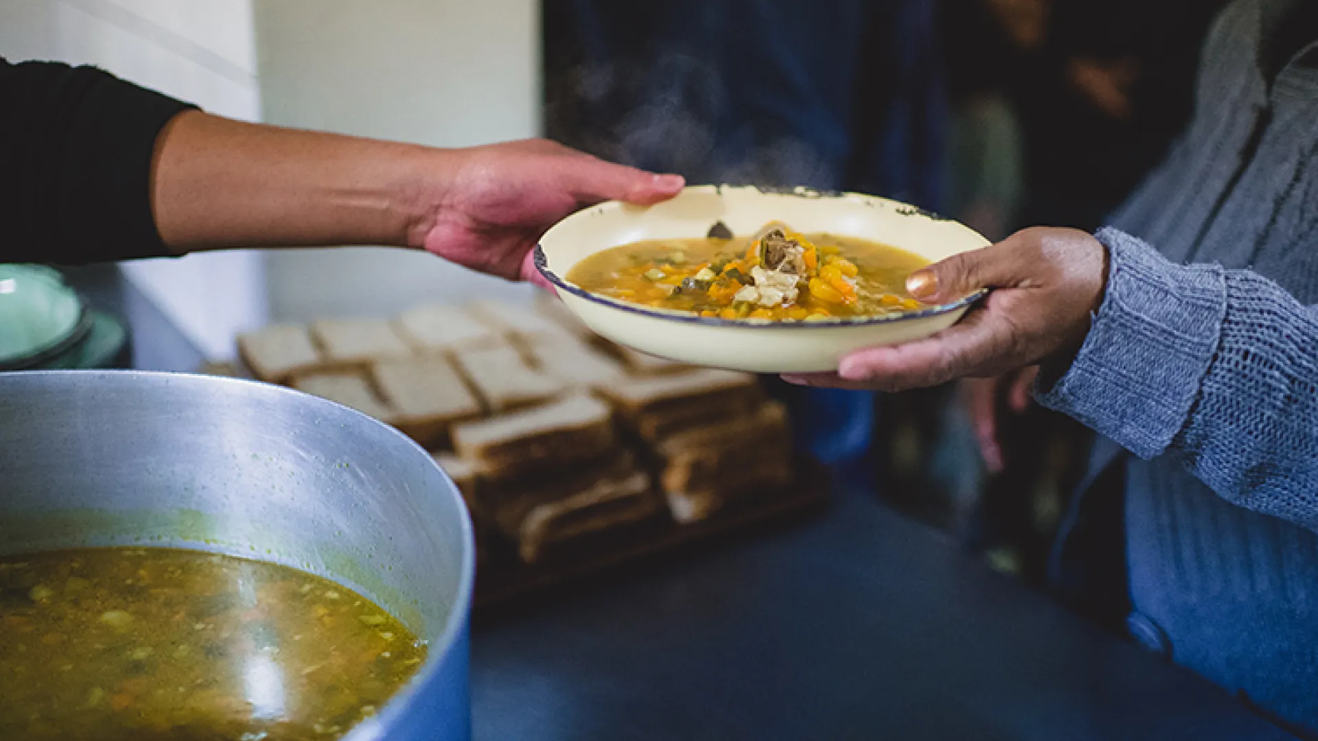 One hand handing another hand a bowl of food
