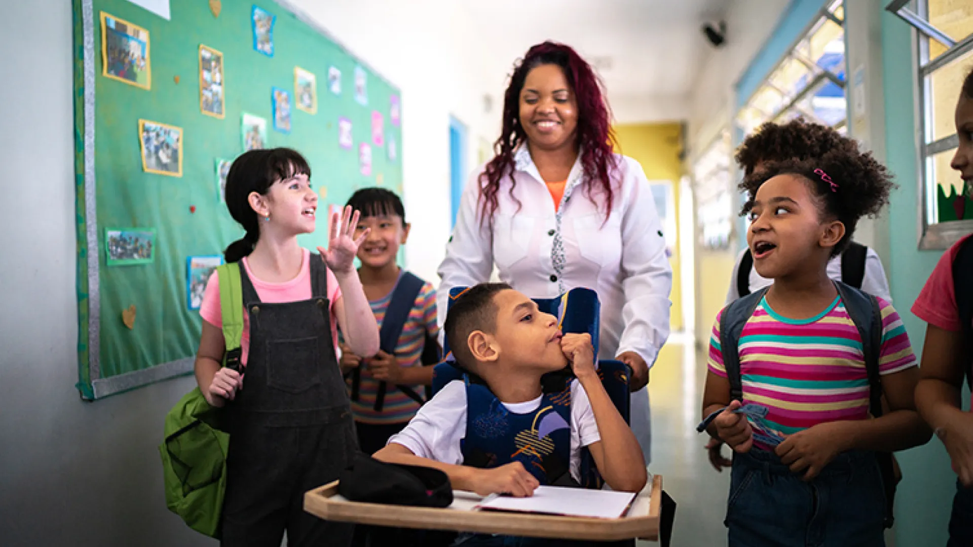 Teacher and diverse group of students in school hallway