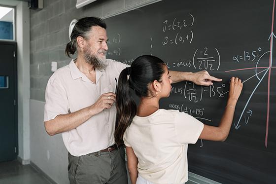 High school math teacher and student at chalkboard
