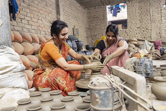 Two Indian women working together at a pottery wheel