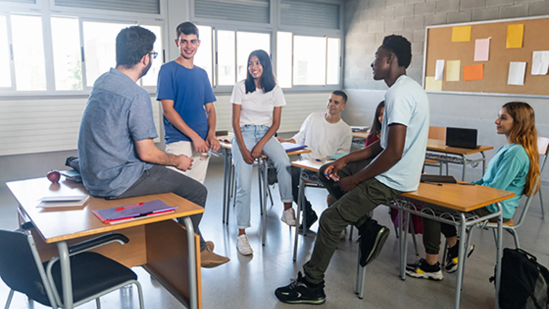 High school students chatting with teacher in classroom