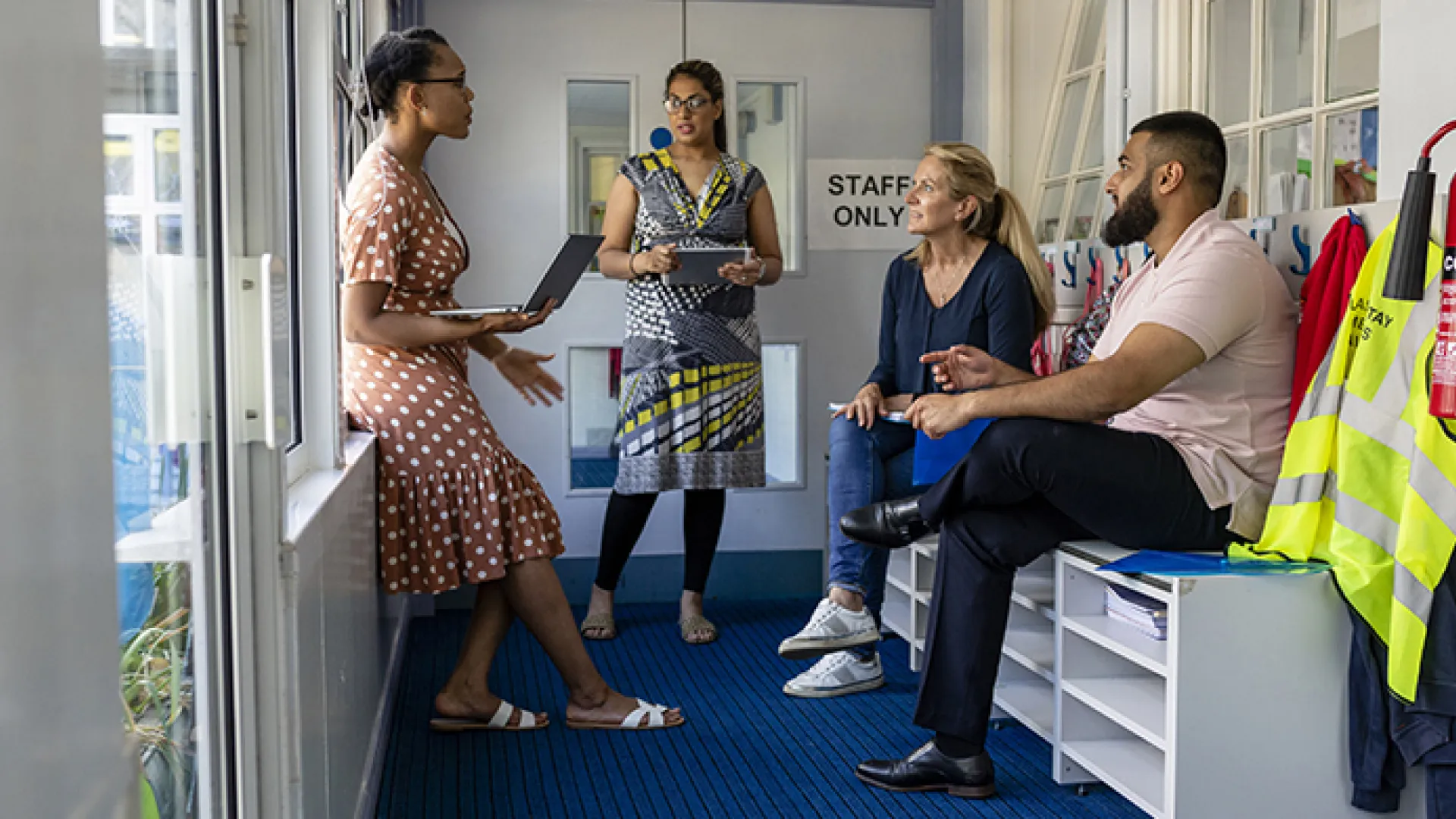 Teachers in conversation in school coatroom