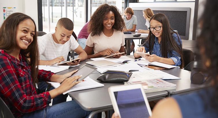Group of happy diverse teens doing homework