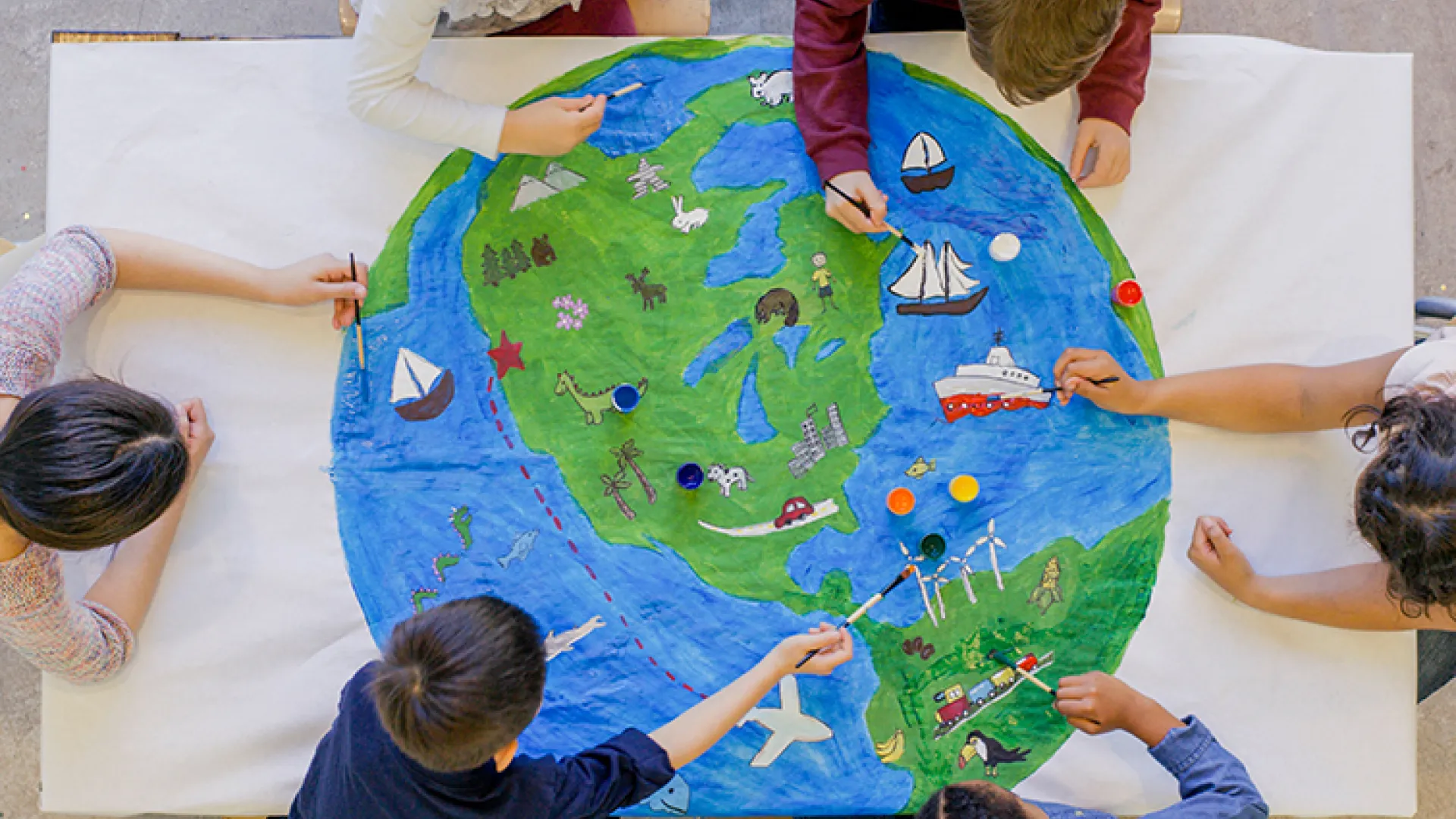 Young children painting colorful world map