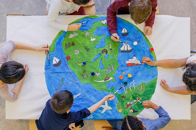 Young children painting colorful world map
