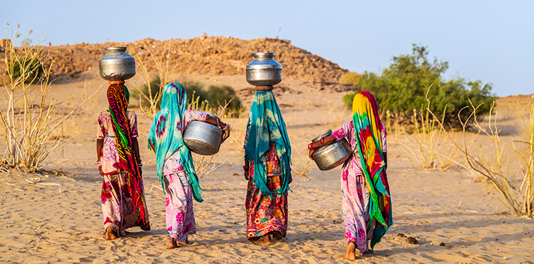 Indian young girls carrying water from well, desert village, India