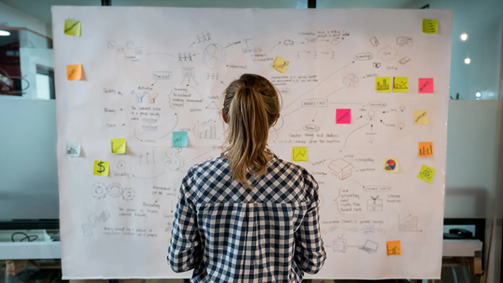 Young worker at strategy board with post-it notes