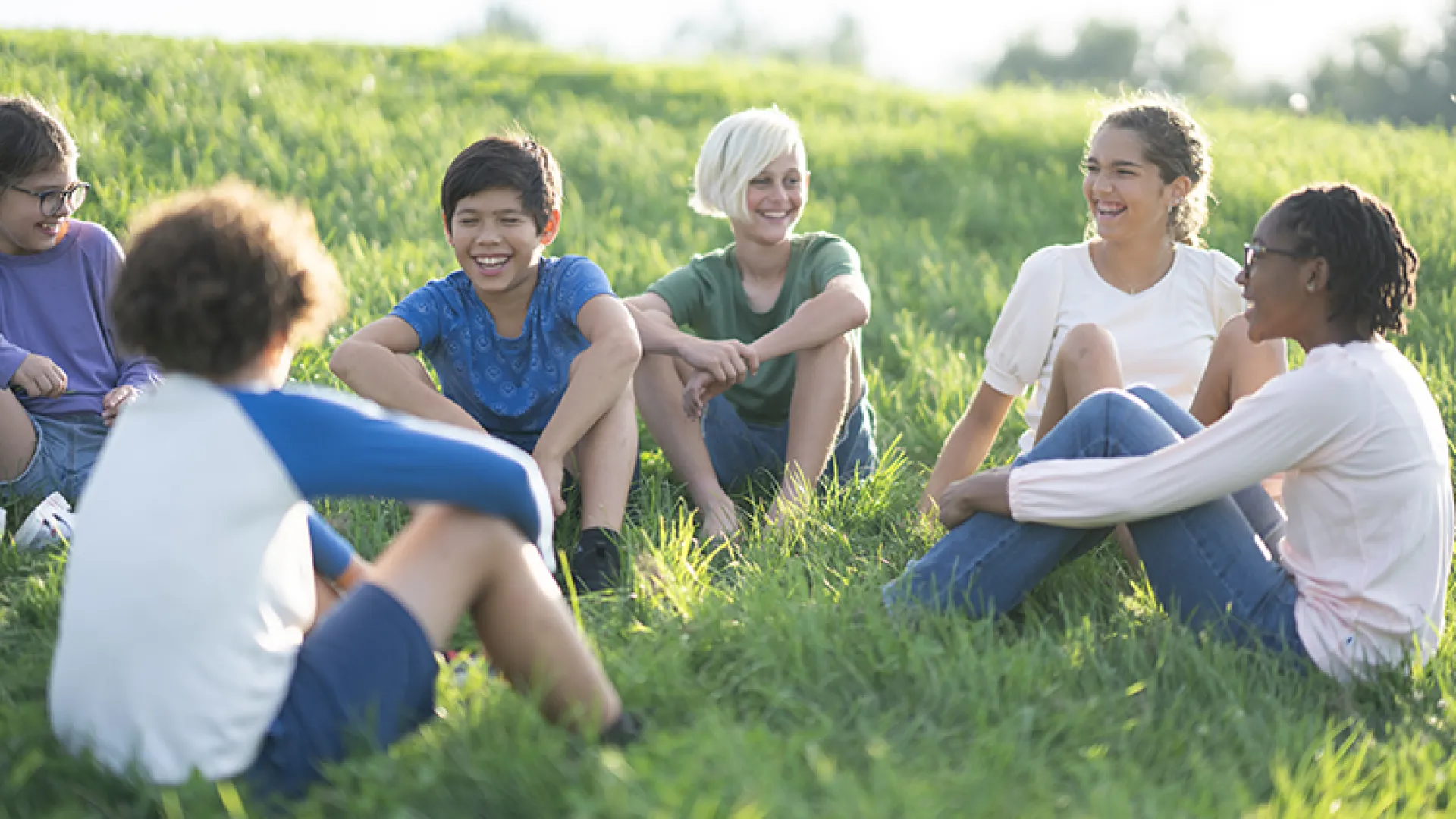 Middle school kids sitting in the grass