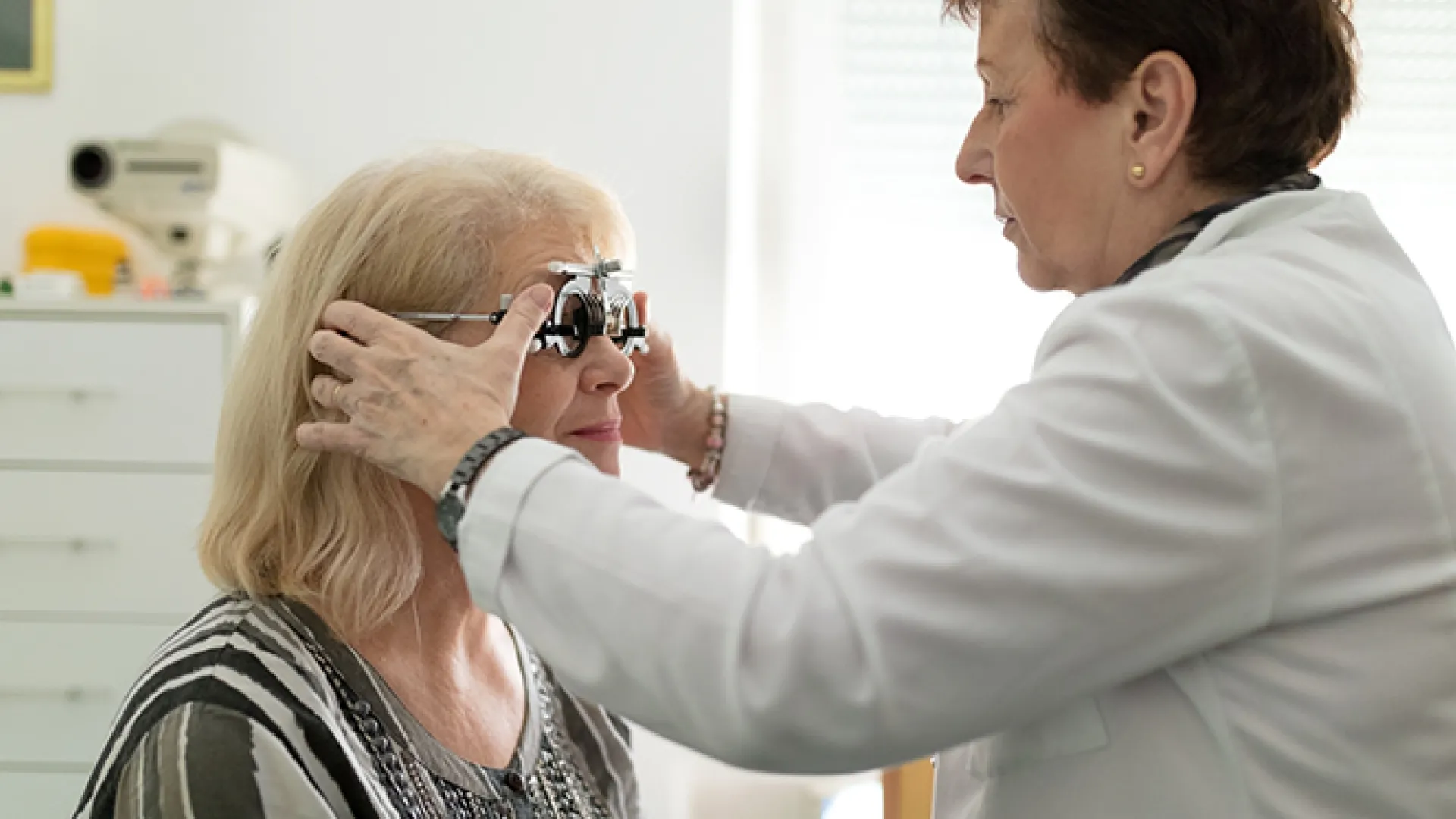 Optometrist adjusting test frame for patient