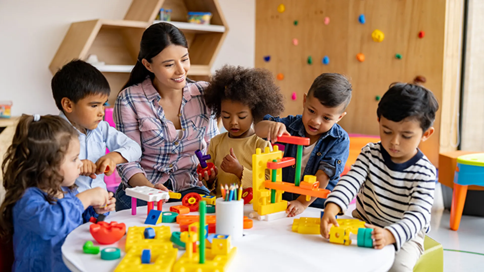 Preschool teacher playing blocks with young students