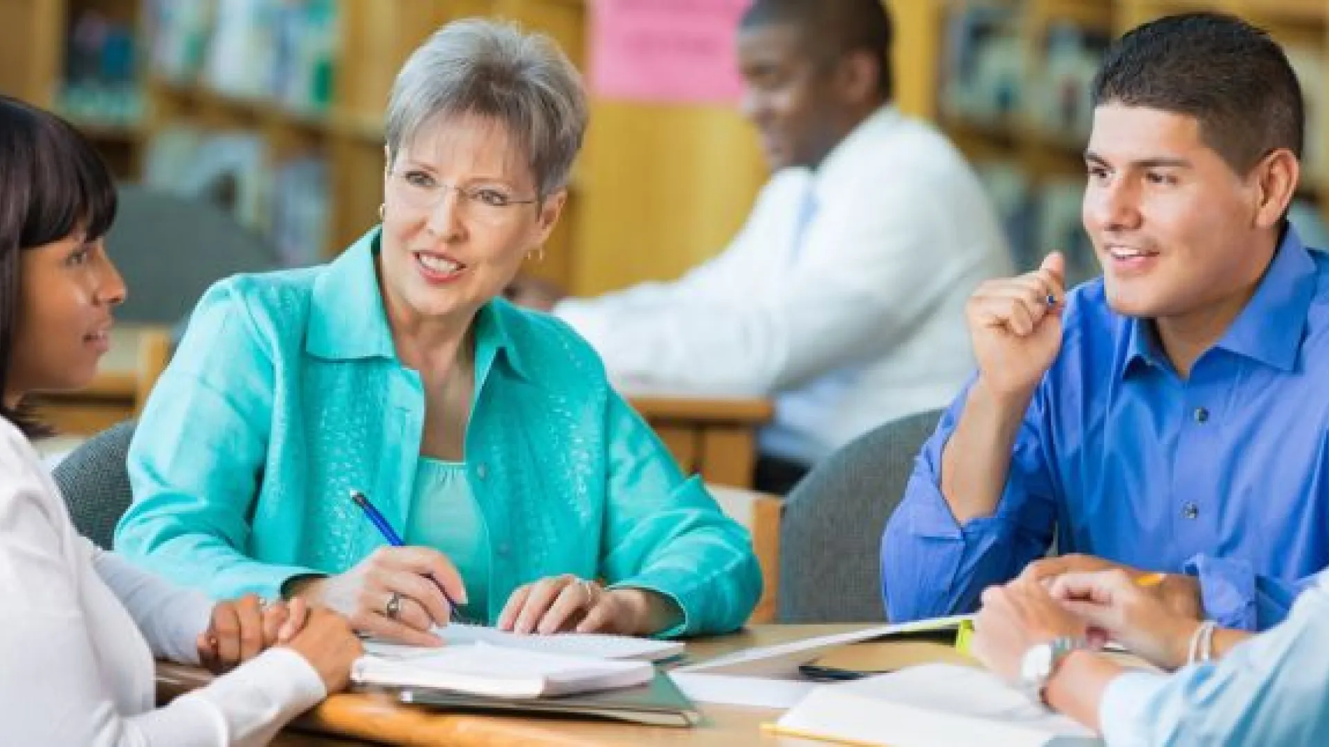 Four teachers meeting in a library 