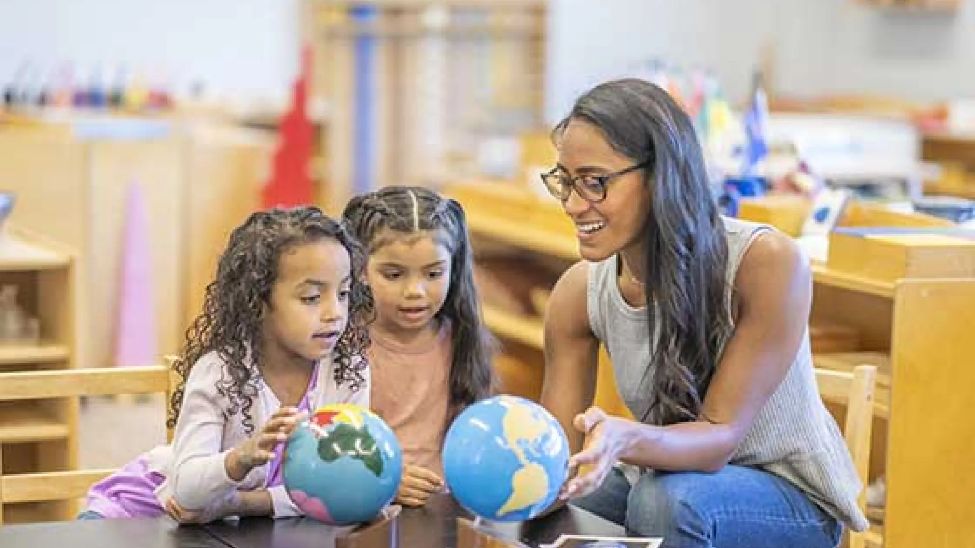 teacher and young children looking at globes in classroom