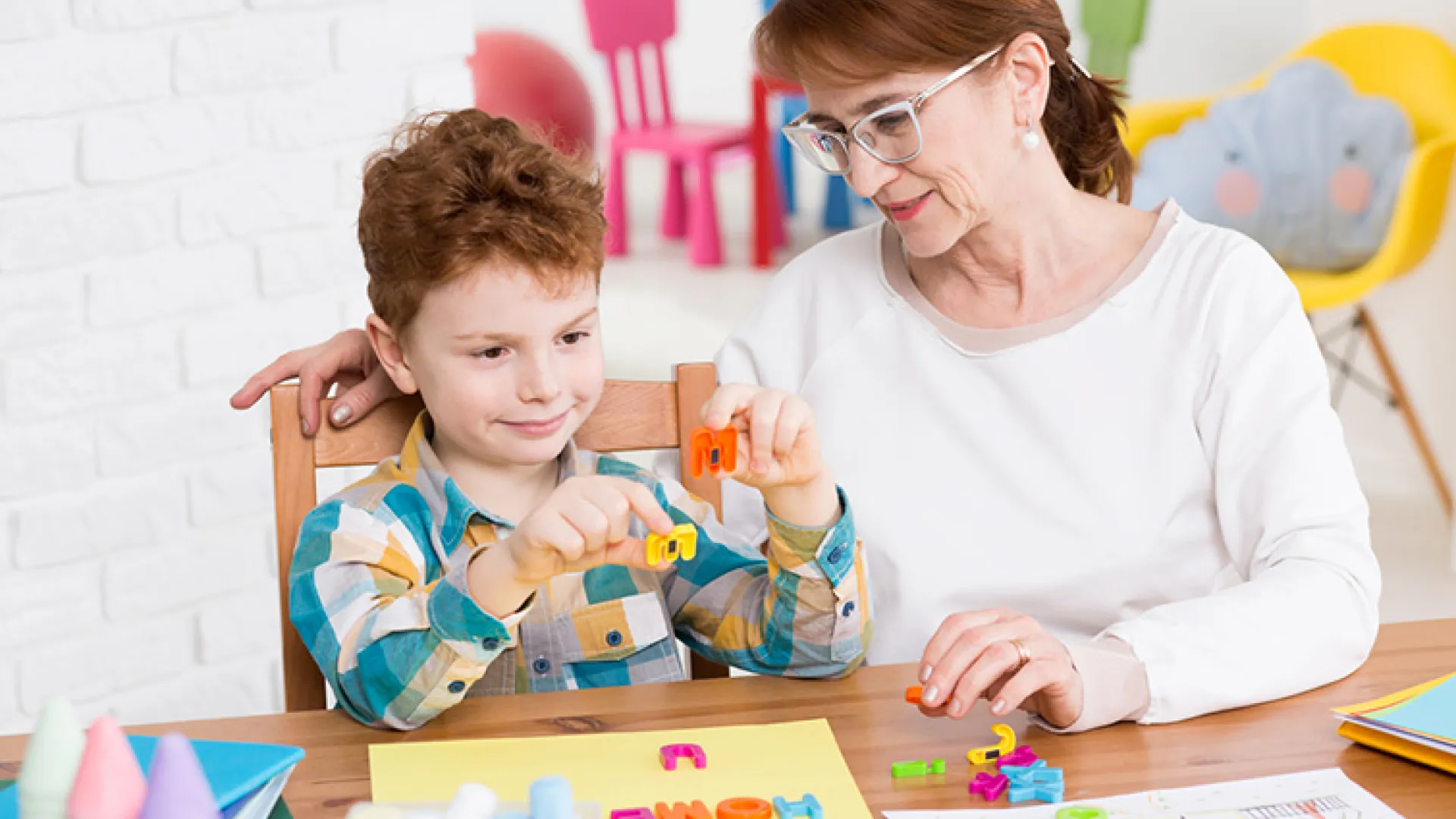 Teacher working with young student on letters