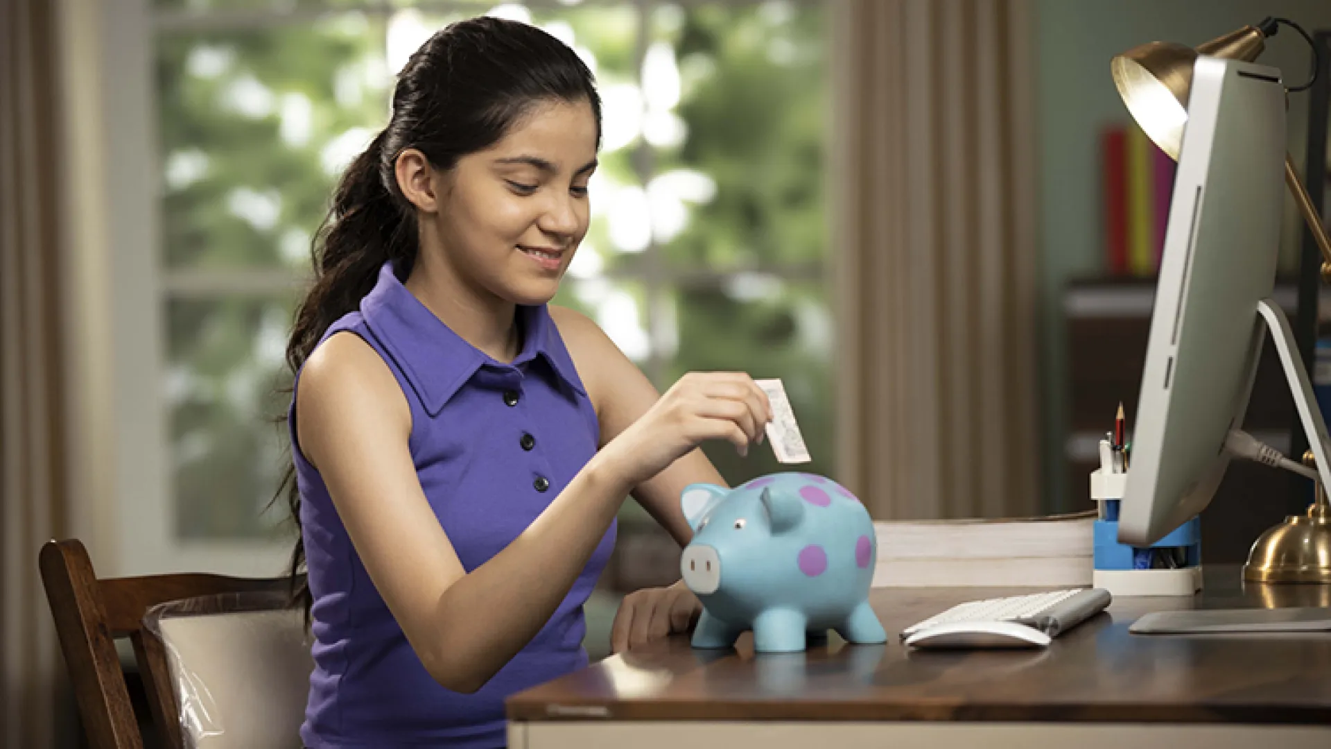 girl putting money in piggybank