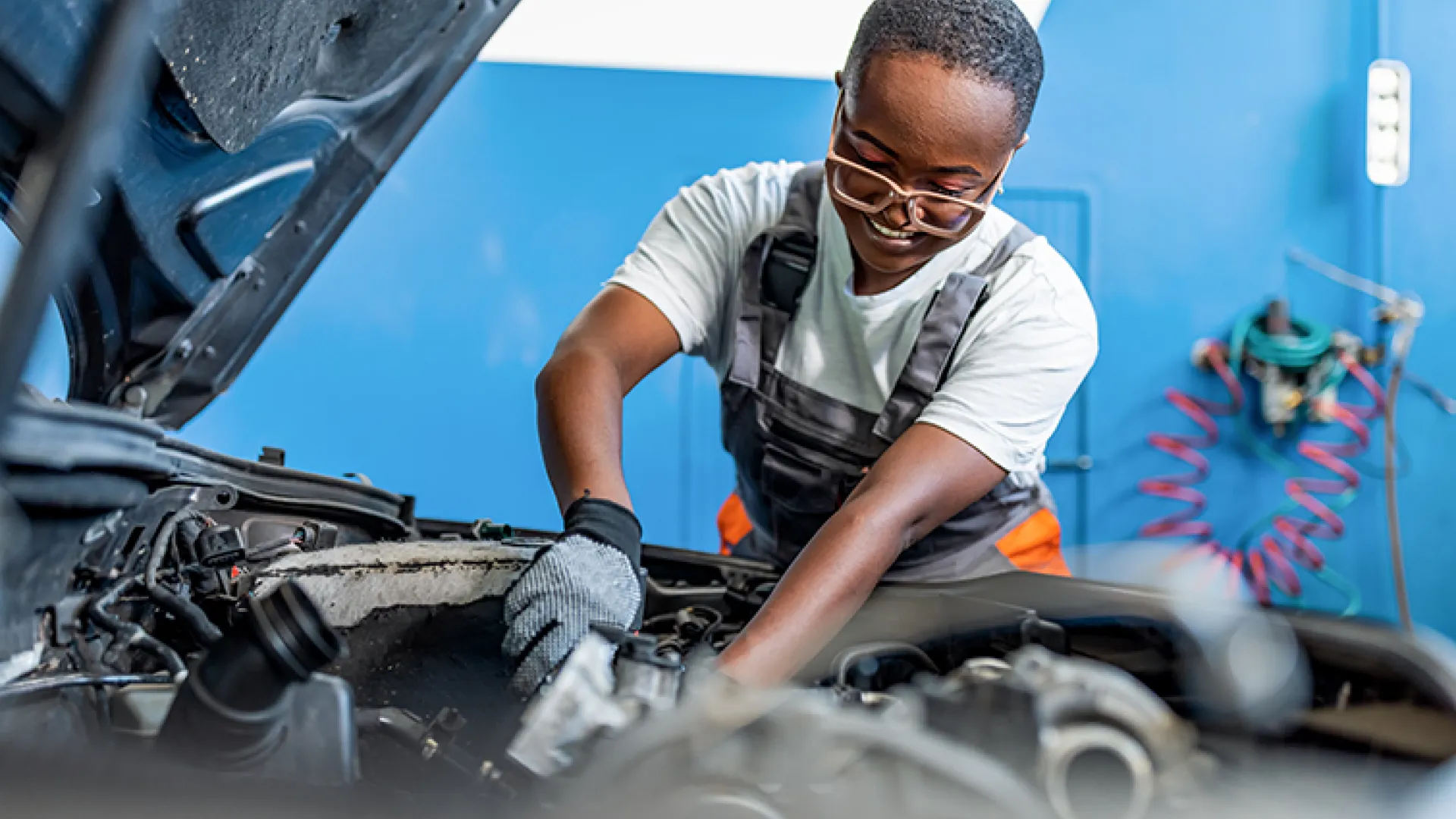 female mechanic working under hood of car
