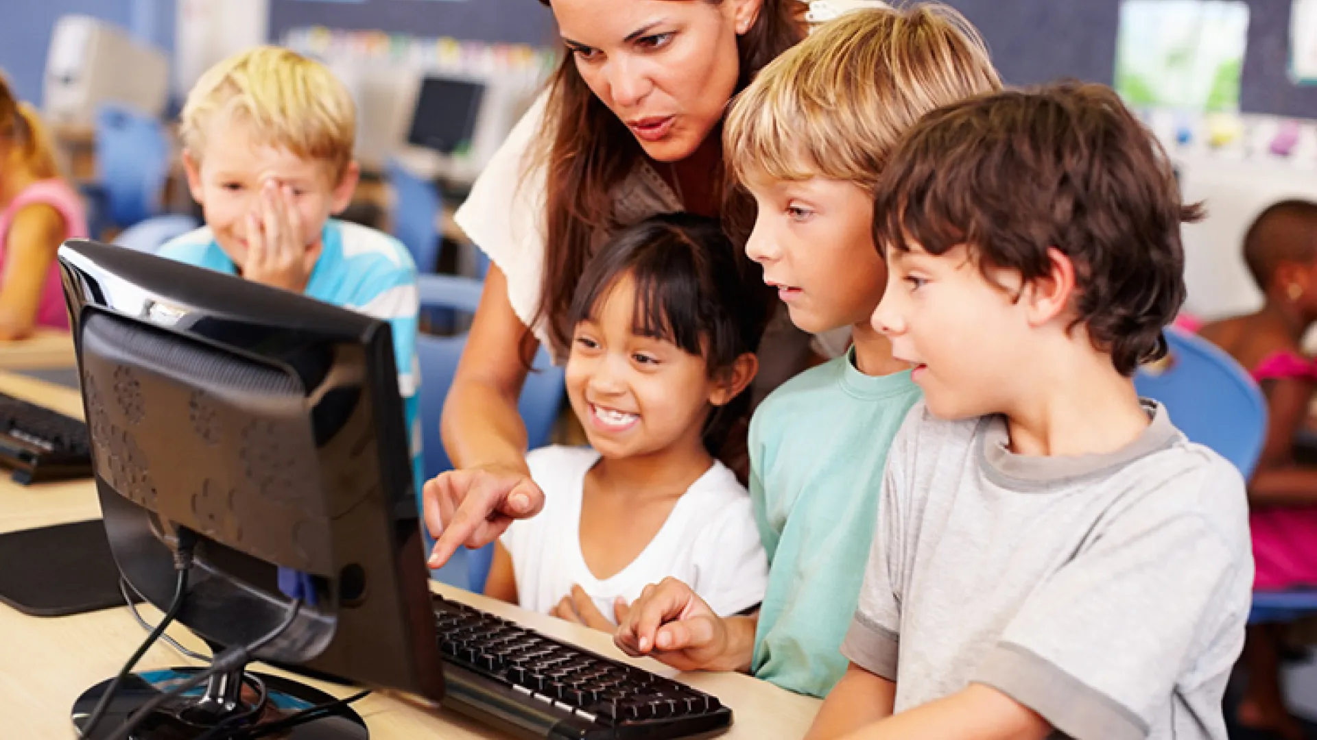 teacher working with students on a computer