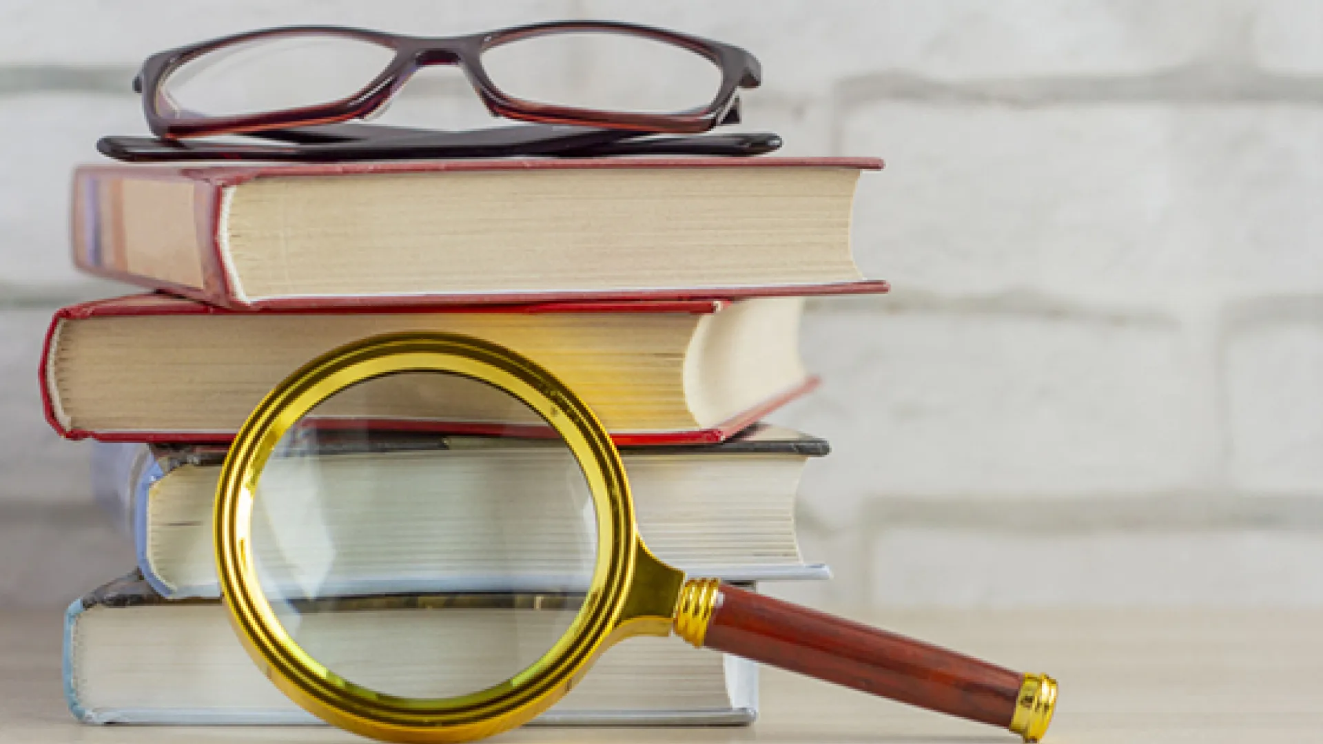 stack of books with magnifying glass