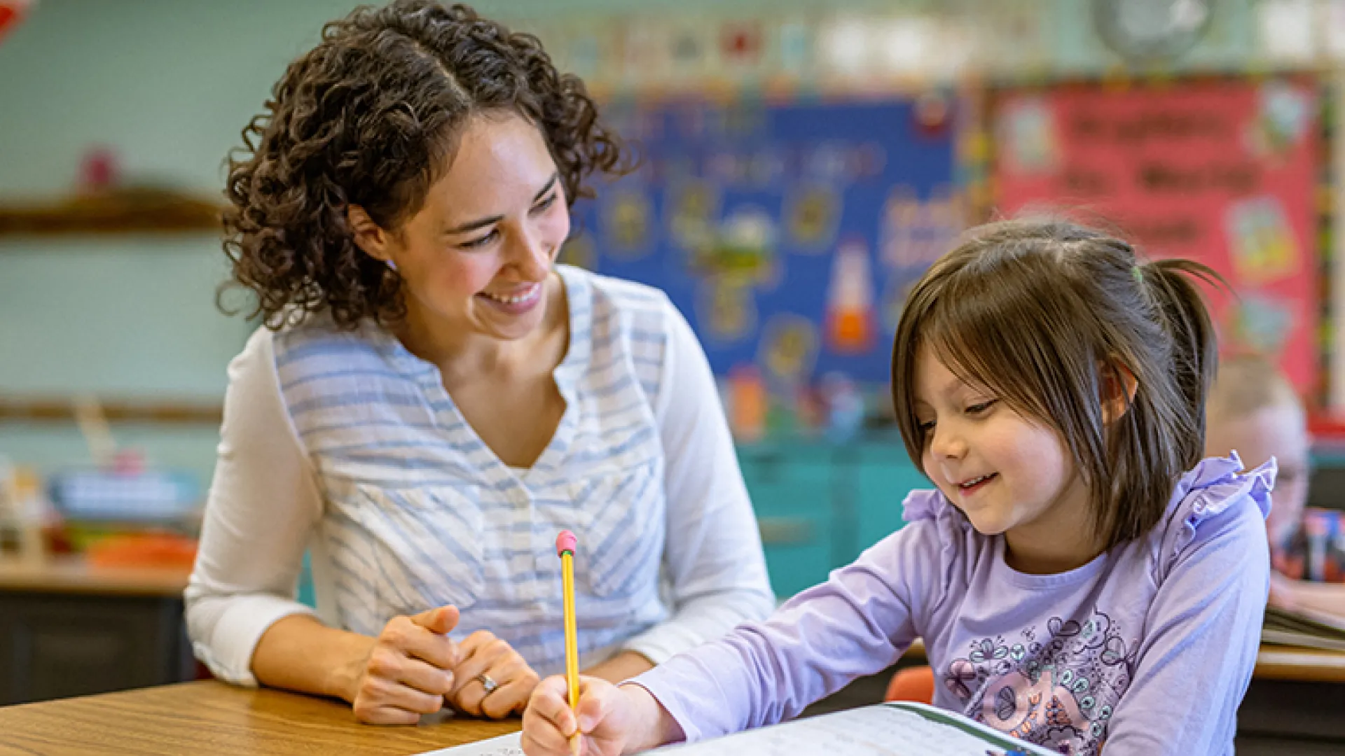 Teacher and young female student working together over a workbook