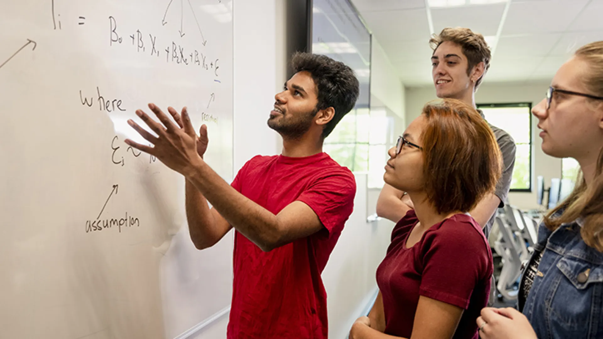 College students working a math problem at a whiteboard