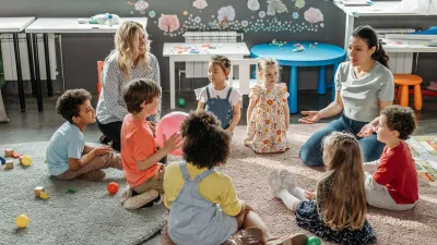 Two teachers instructing elementary students seated in a circle on the floor