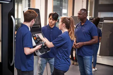 Engineer showing apprentices how to work a machine