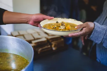 One hand handing another hand a bowl of food