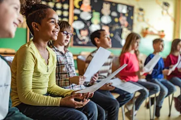 Smiling kids sitting in a row at school