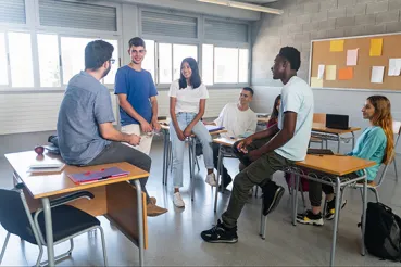 High school students chatting with teacher in classroom