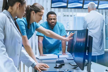 team of healthcare workers looking at computer monitor