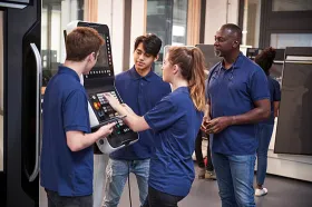 Engineer showing apprentices how to work a machine