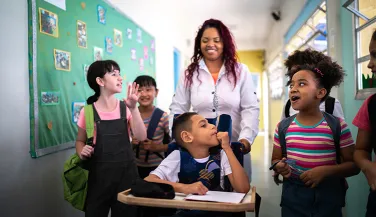 Teacher and diverse group of students in school hallway