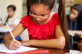 Young female student writing at school desk