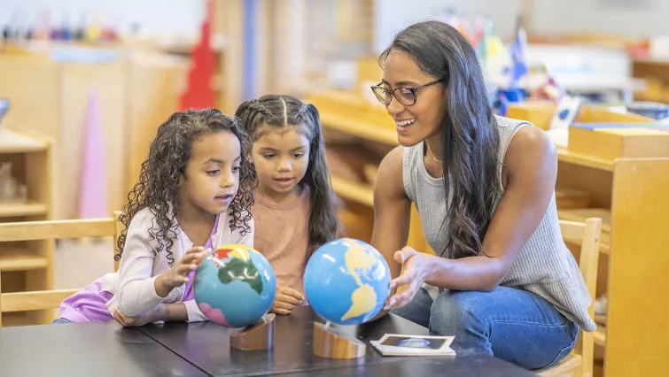 Teacher with young students working with two globes