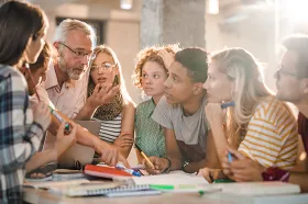 Mature teacher teaching group of college students at campus