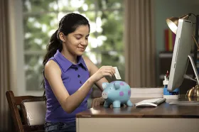 girl putting money in piggybank