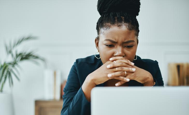 Shot of a young businesswoman frowning while using a laptop