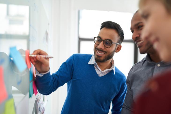 Portrait of an indian man in a diverse team of creative millennial coworkers in a startup brainstorming strategies