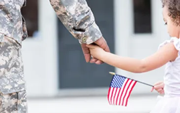 Image of girl with flag holding soldier's hand