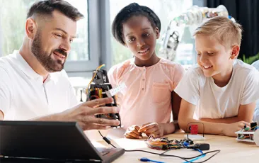 Image of teacher and students building a robot