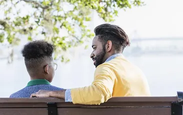Image of man on a bench with his arm around a boy