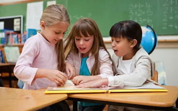 Image of three girls excitedly looking at a book