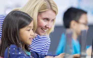 Teacher and student working on laptop