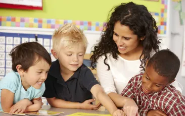 Teacher with happy young students working on a book