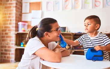Teacher and young student playing with toy phone